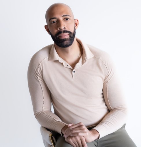 ODU alumnus Damien Geter sits in front of a white backdrop. 