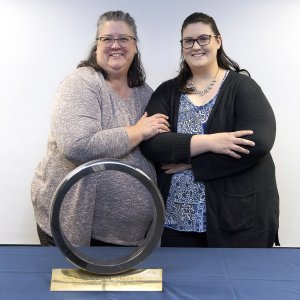 Two women stand together with a metal ring