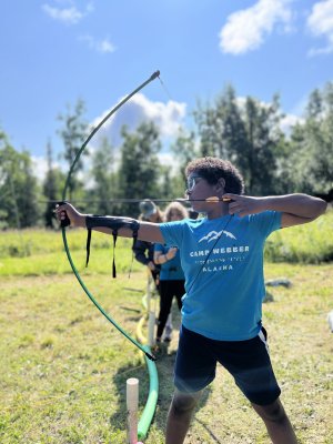 a young person holds a bow and arrow 