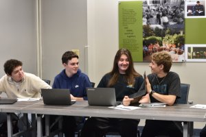 Four high school students look at a laptop
