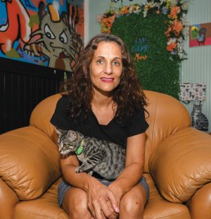 woman sits in chair holding cat 