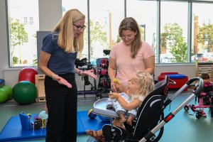 Two women speaking with a pediatric patient in a wheelchair