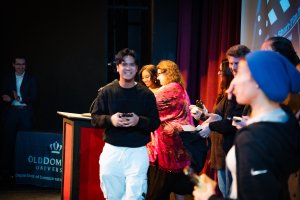 A student walks across a stage holding an award.