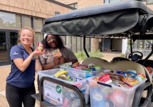 Two women load donation items onto a golf cart.