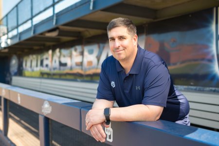 a man in a blue shirt stands in a baseball dugout 