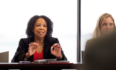 A woman in a suit sits at a conference table 