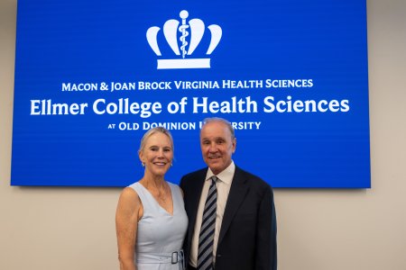 two people stand in front of a sign 