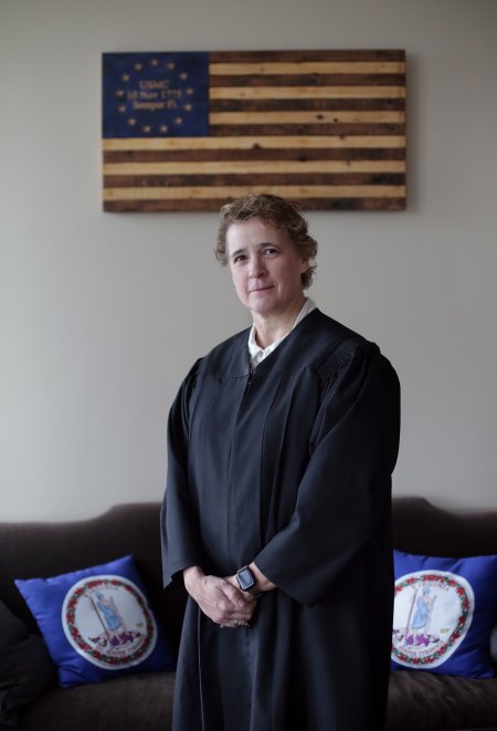 a women in a judge's robe stands in front of a couch 