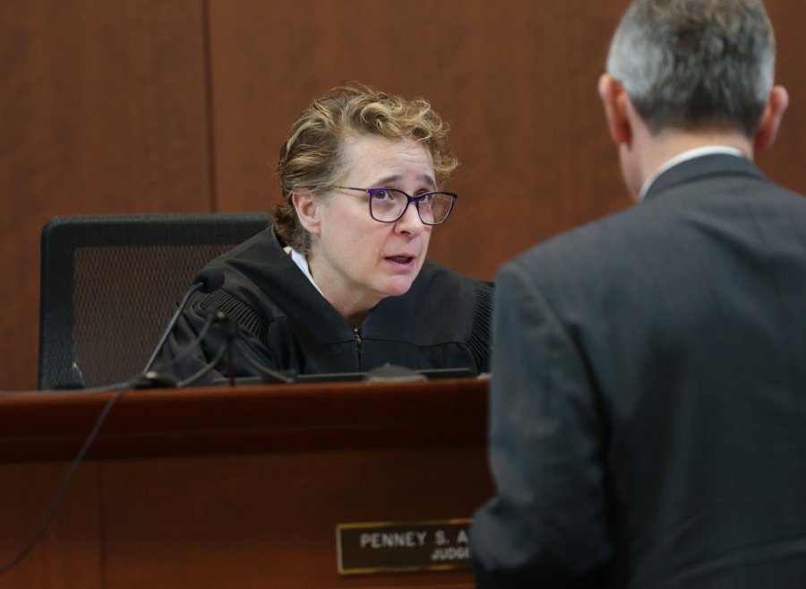 a woman in judge's robes sits at a judge's bench 