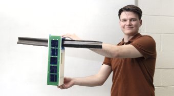 graduate student Christopher Schappi holding a prototype.