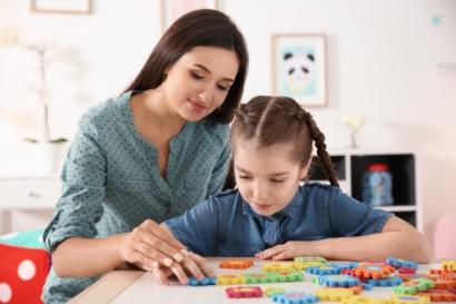 Young woman and little girl with autistic disorder playing a